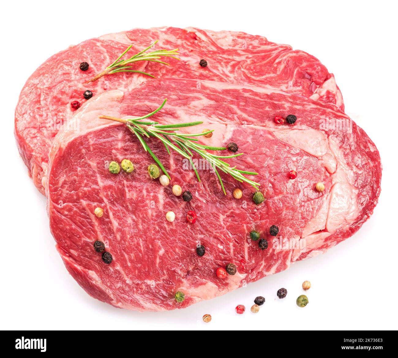 Raw ribeye steak with peppercorn and rosemary isolated on white background. Top view. Stock Photo