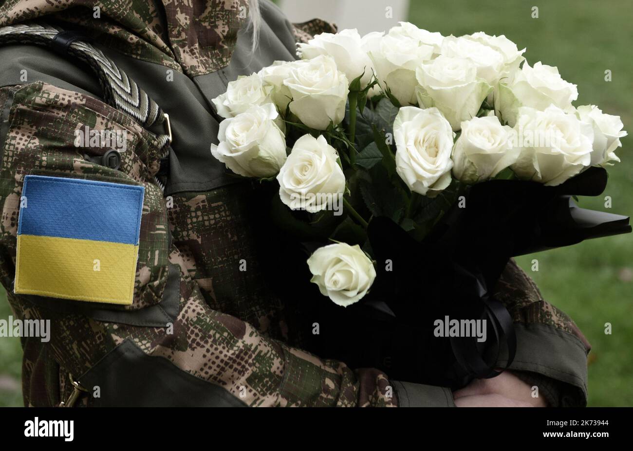 Ukrainian flag on military uniform. Soldier holds flowers. A funerals
