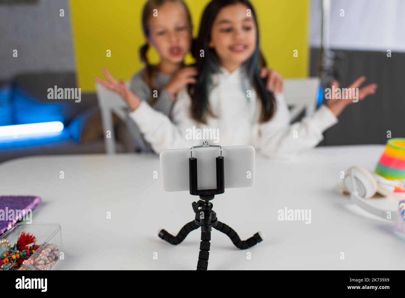 selective focus of smartphone on phone holder near bloggers talking on blurred background Stock Photo