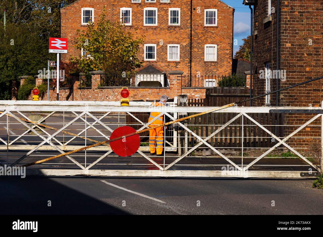 Level crossing gates being closed by guard on the old manual level crossing at Heckington village, Lincolnshire, England. Stock Photo