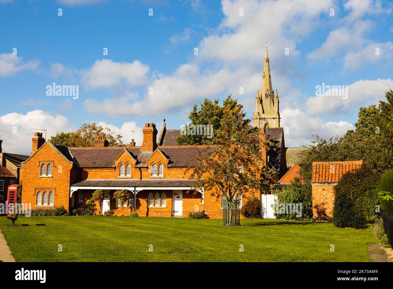 Henry Godson Alms Houses 1886, with St Andrews parish church behind. Heckington village, Lincolnshire, England. Stock Photo
