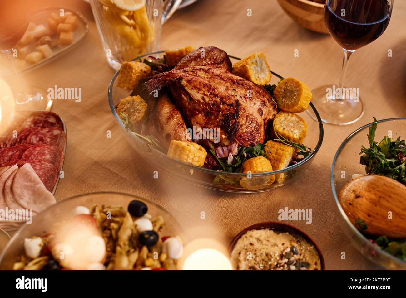 Close up of roasted chicken on dinner table with rustic homemade dishes in cozy setting Stock Photo