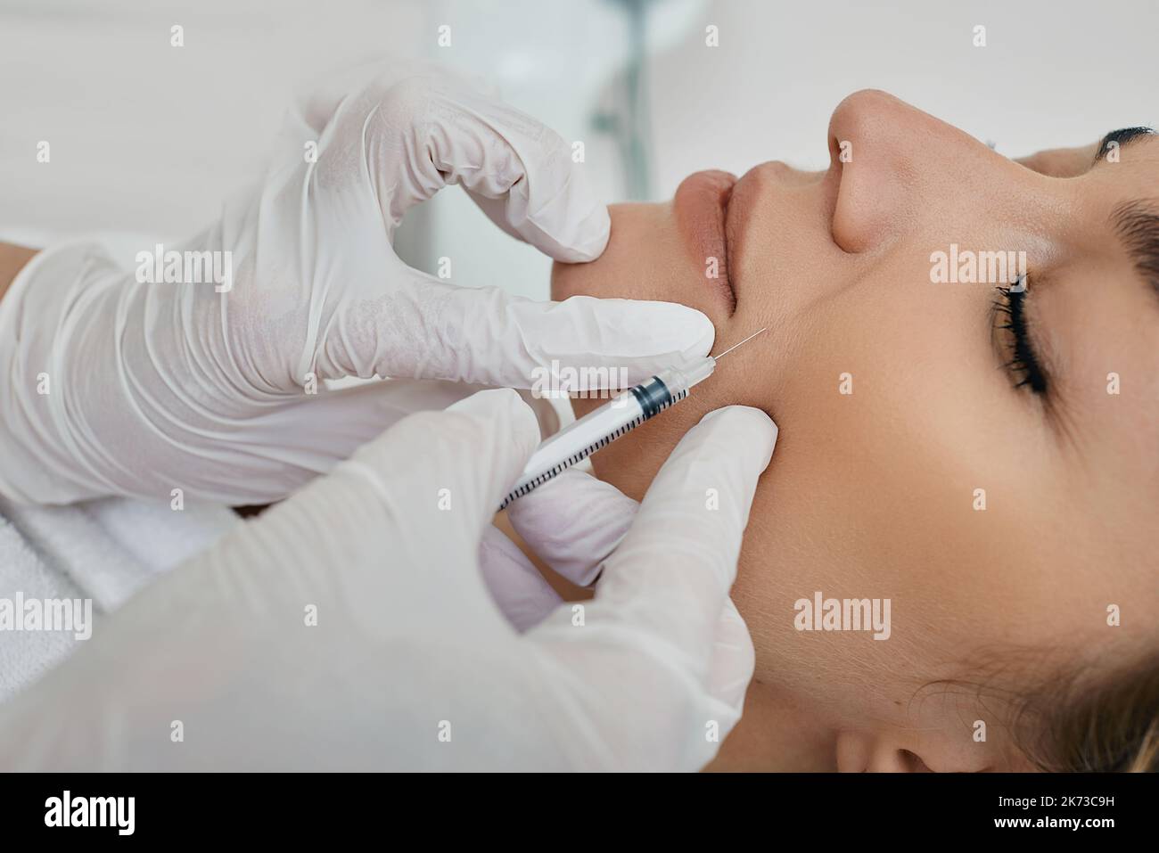 Female face with mimic wrinkles near mouth, beautician doing injection into nasolabial folds. Botulinum toxin injection for remove wrinkle Stock Photo