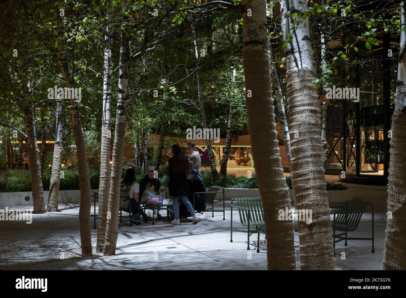 Seating area below trees with dappled lighting. Exchange Square, London, United Kingdom. Architect: DSDHA, 2022. Stock Photo