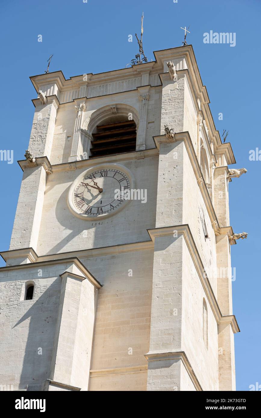 Bell tower of Notre-Dame-des-Anges Collegiate Church in L'Isle-sur-la-Sorgue with clock with Roman numbers engraved on the facade of the building. Stock Photo
