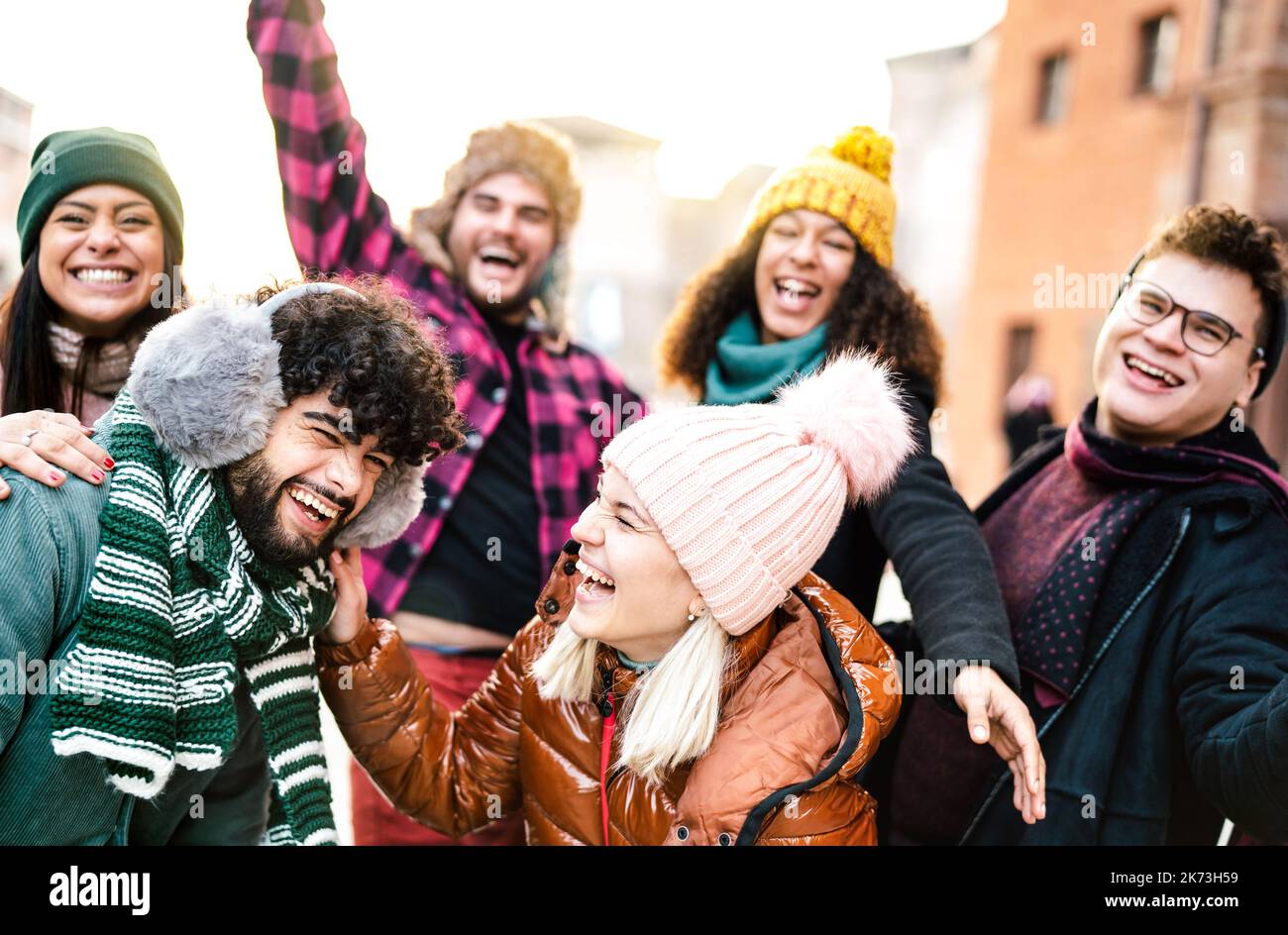 International guys and girls taking funny face selfie wearing warm fashion clothes - Happy life style concept with milenial people having fun together Stock Photo
