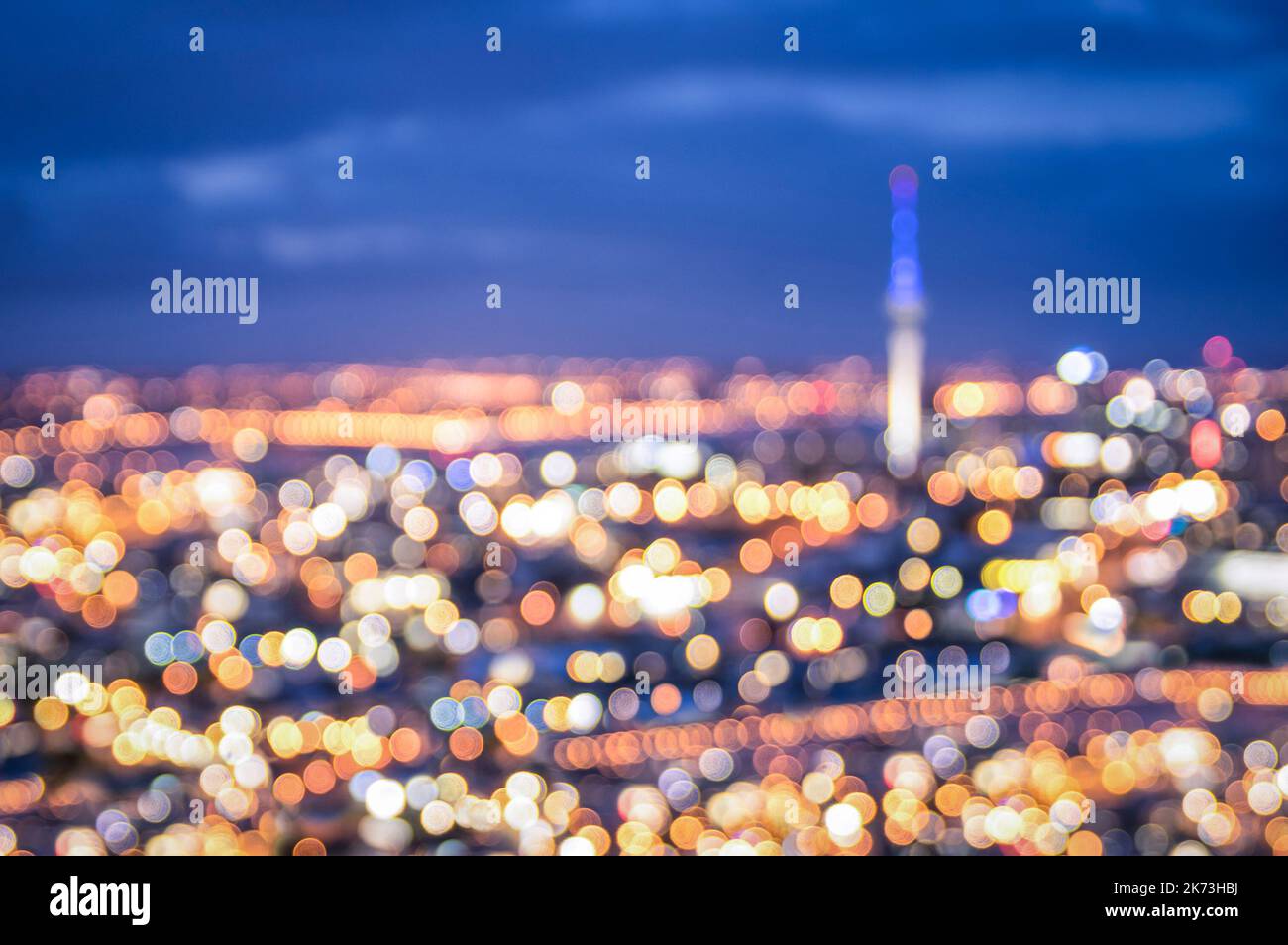 Bokeh of Auckland skyline from Mount Eden after sunset during the blue hour - New Zealand modern city with spectacular nightscape panorama - Blurred d Stock Photo