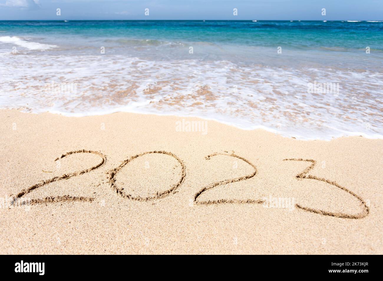 New Year 2023, lettering on the beach with wave Stock Photo