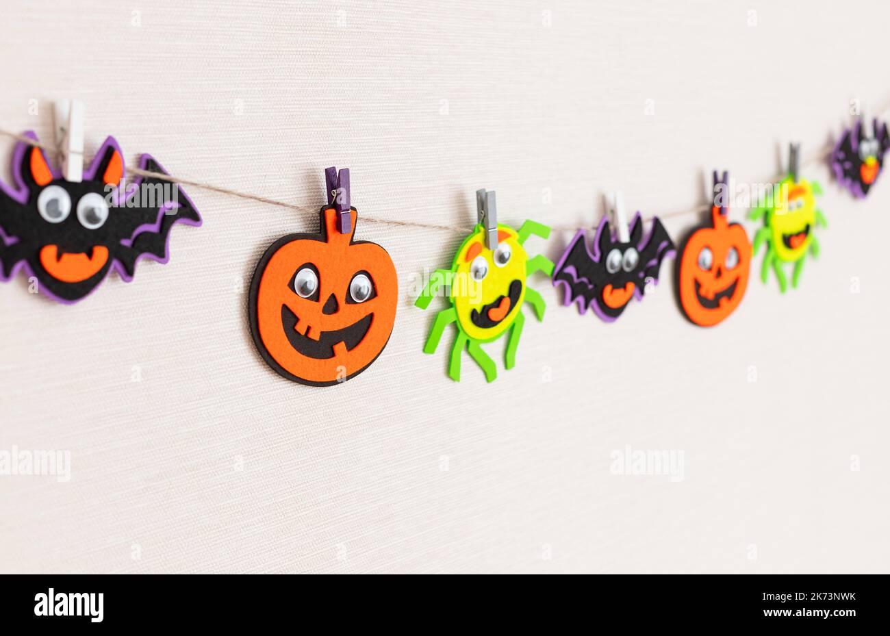 Halloween decoration on wall, felt monsters garland with scary faces Stock Photo