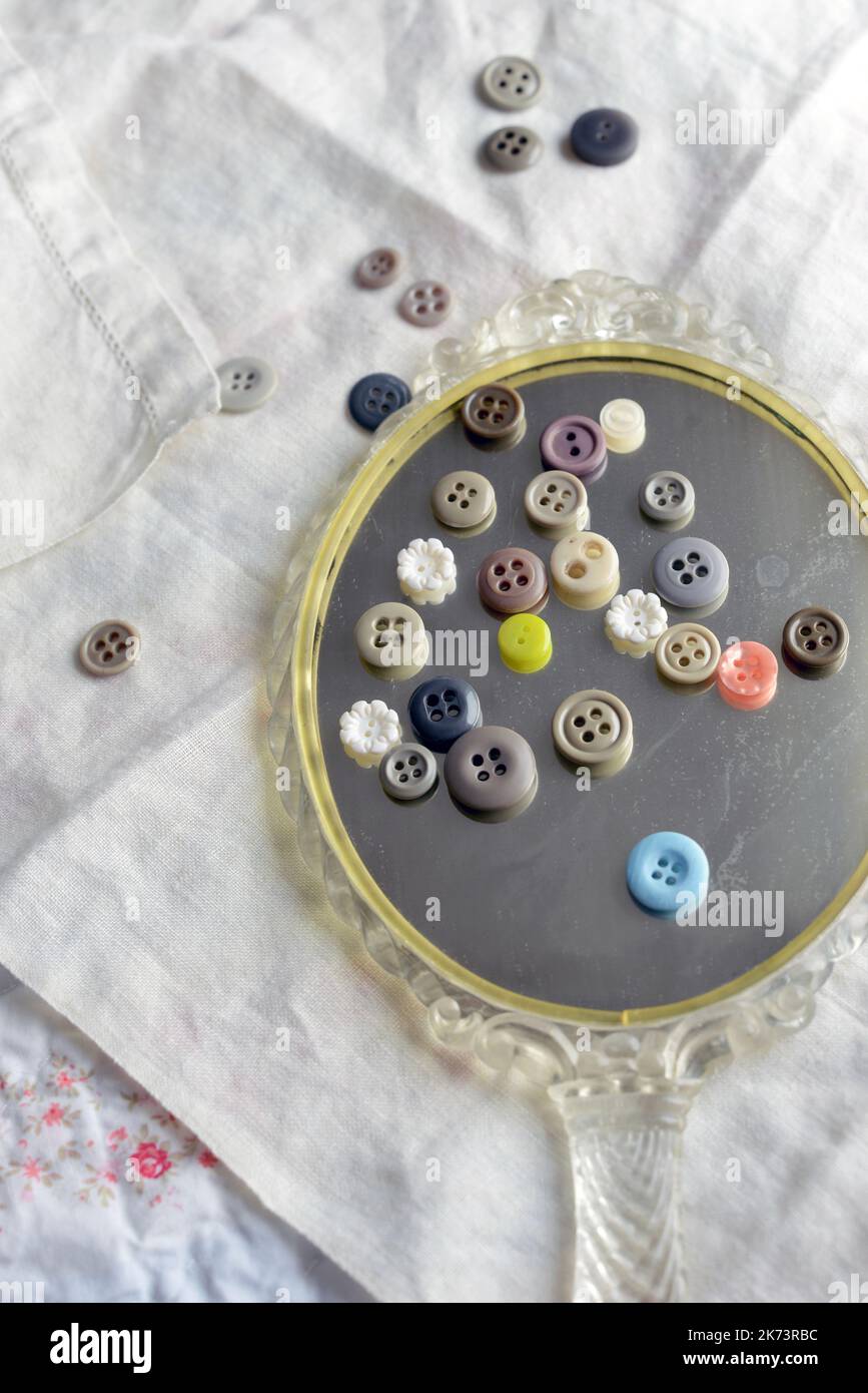 Vintage buttons on an antique mirror on top old linens Stock Photo