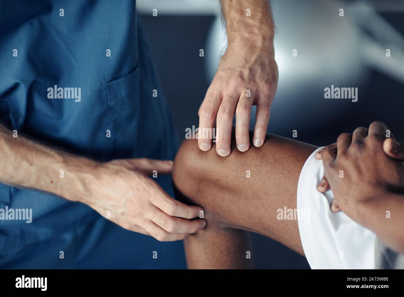 Close-up of doctor examining pain leg of patient during medical exam Stock Photo