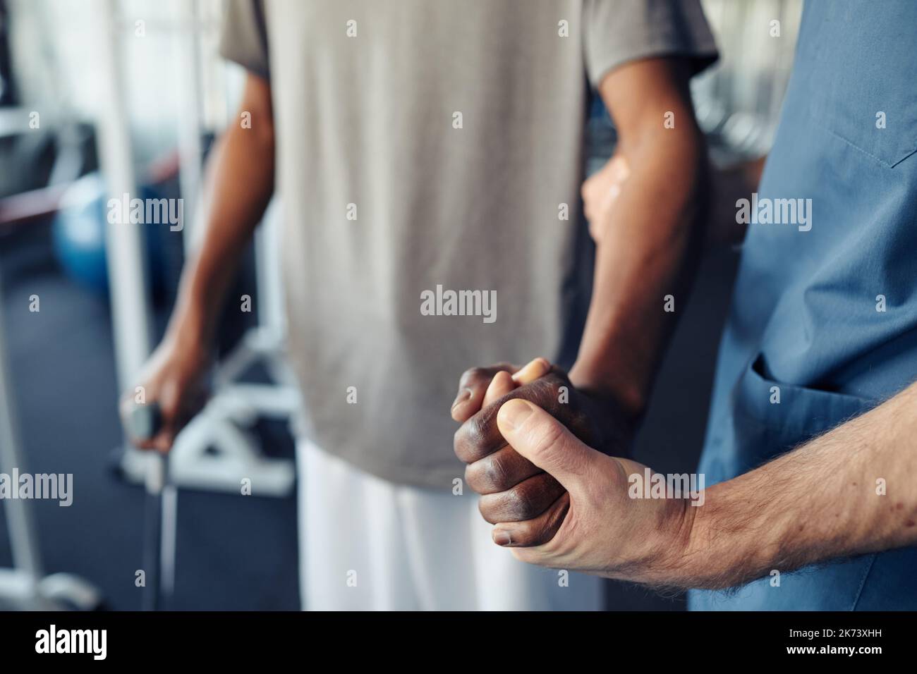 Close-up of male doctor holding hand of patient and helping him to walk again after serious injury Stock Photo