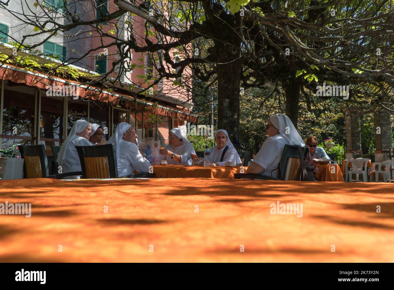 A group of Roman catholic nuns sat  around a table chatting, Montallegro Northern Italy ITA. September 2022. Stock Photo