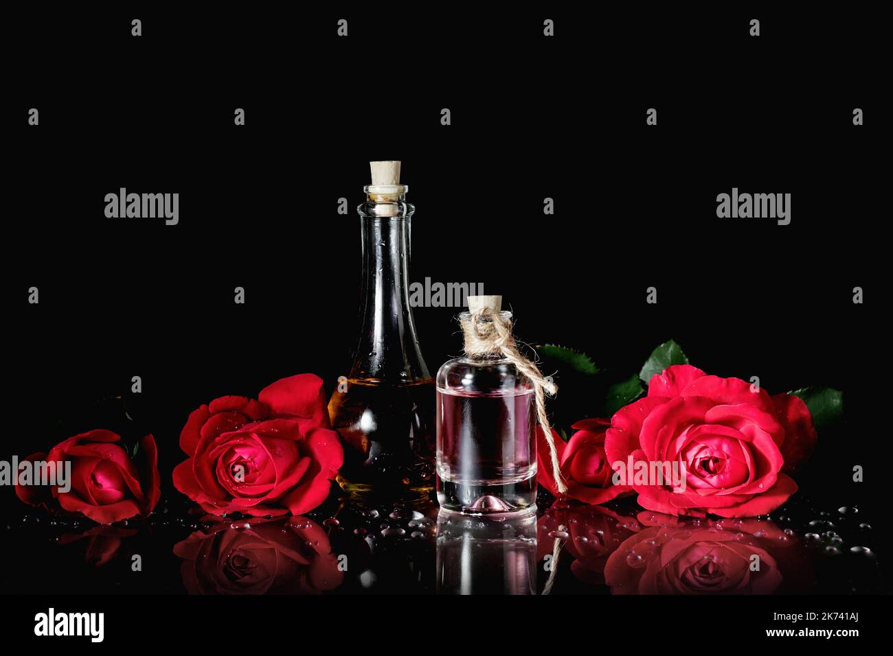 Bottles of perfume and red roses on a black background. Stock Photo