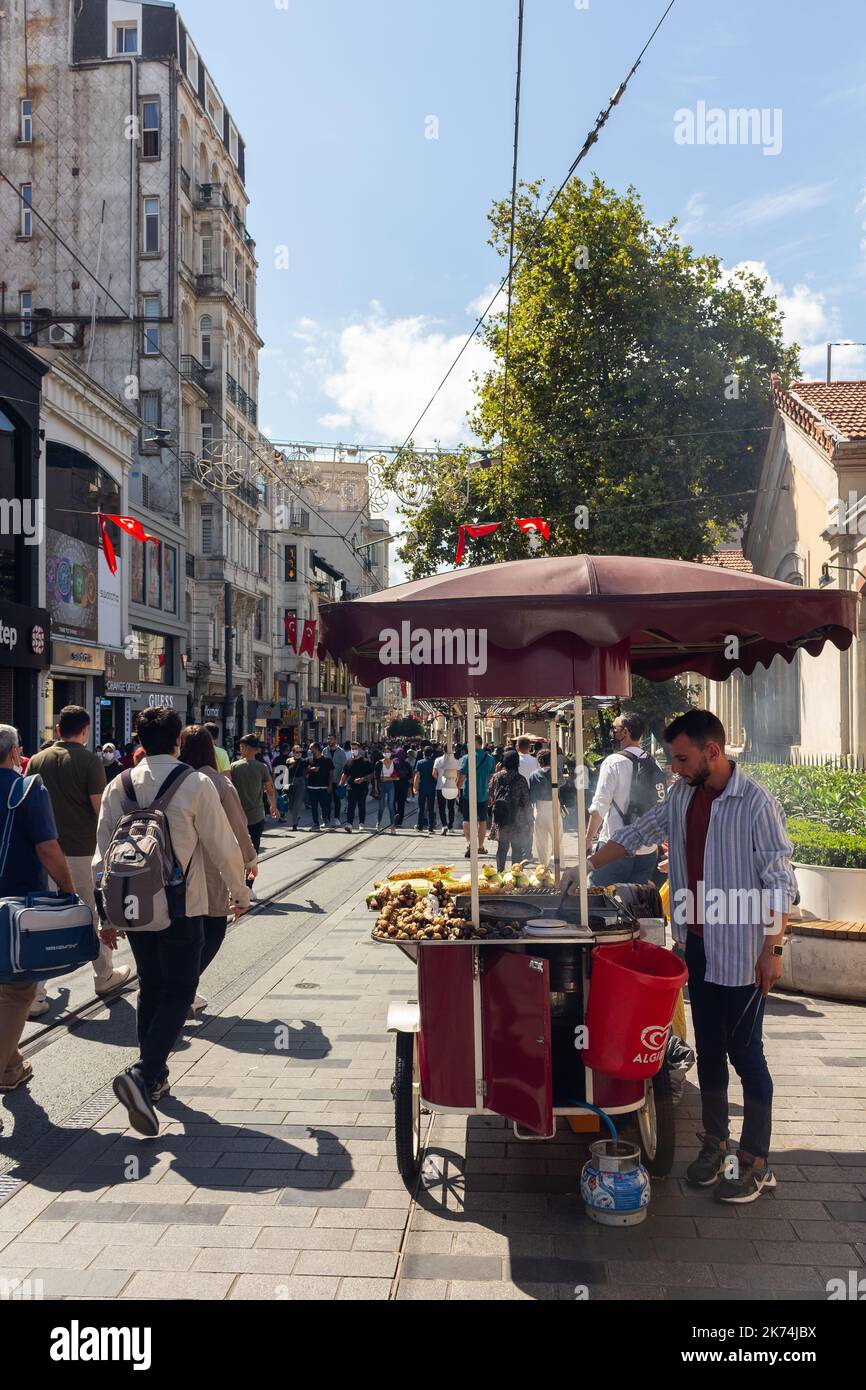 View of people walking and street food seller on Istiklal Avenue the city’s main pedestrian boulevard in Istanbul. The street which is lined with 19th Stock Photo