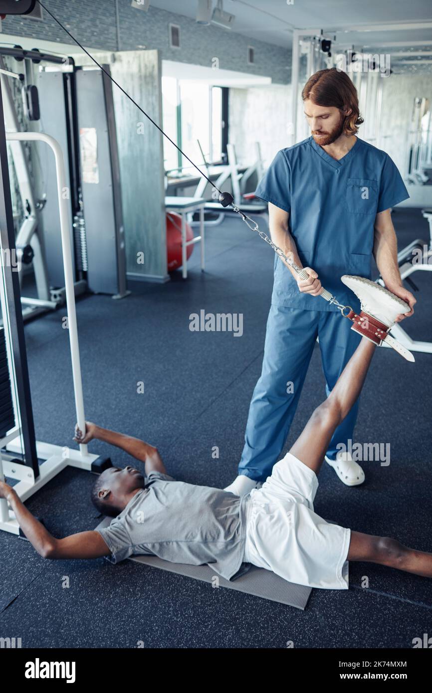 Doctor helping patient to exercise in gym using sport equipment Stock Photo