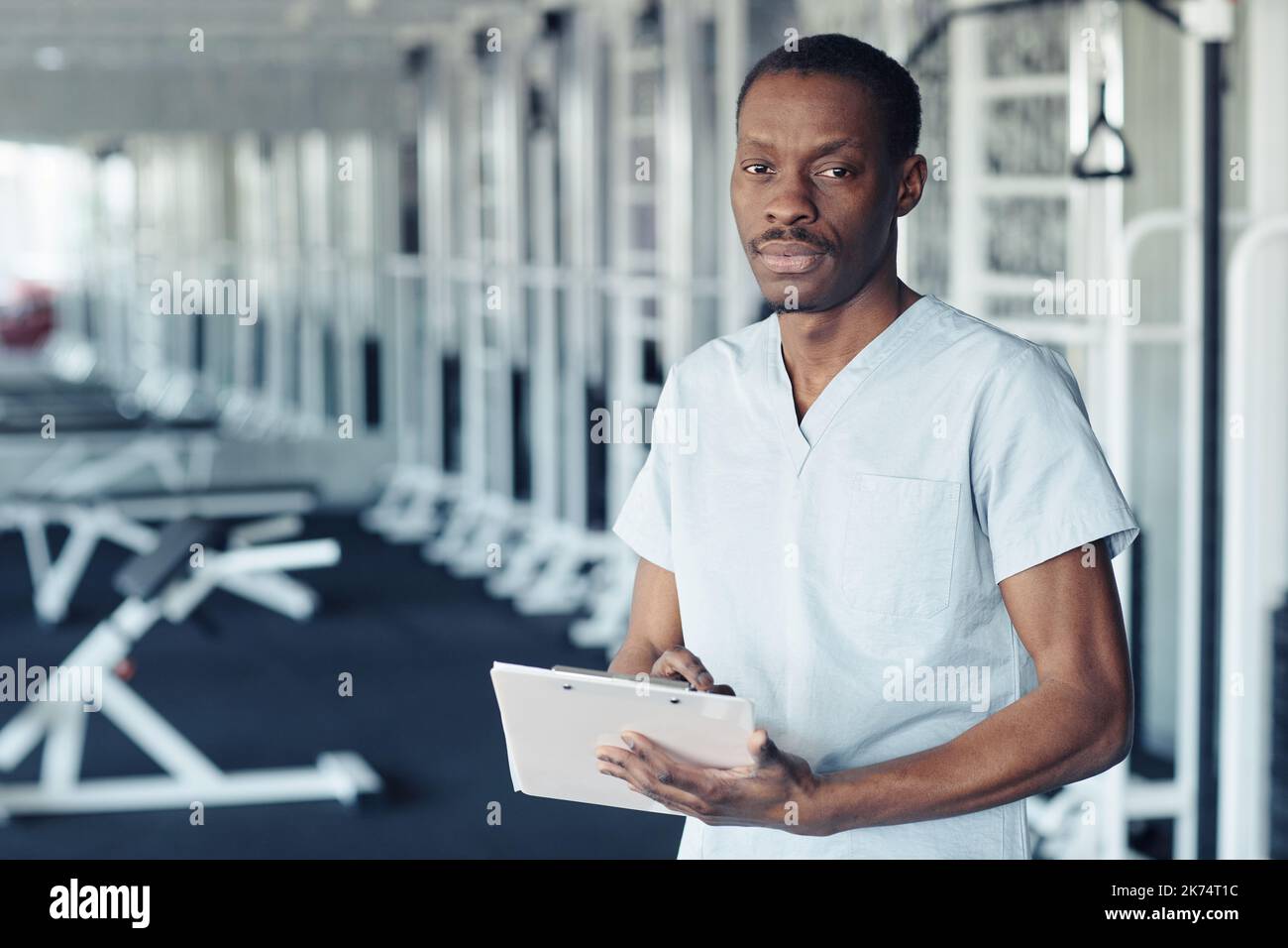 Portrait of African doctor in uniform filling patient medical card while standing in gym Stock Photo