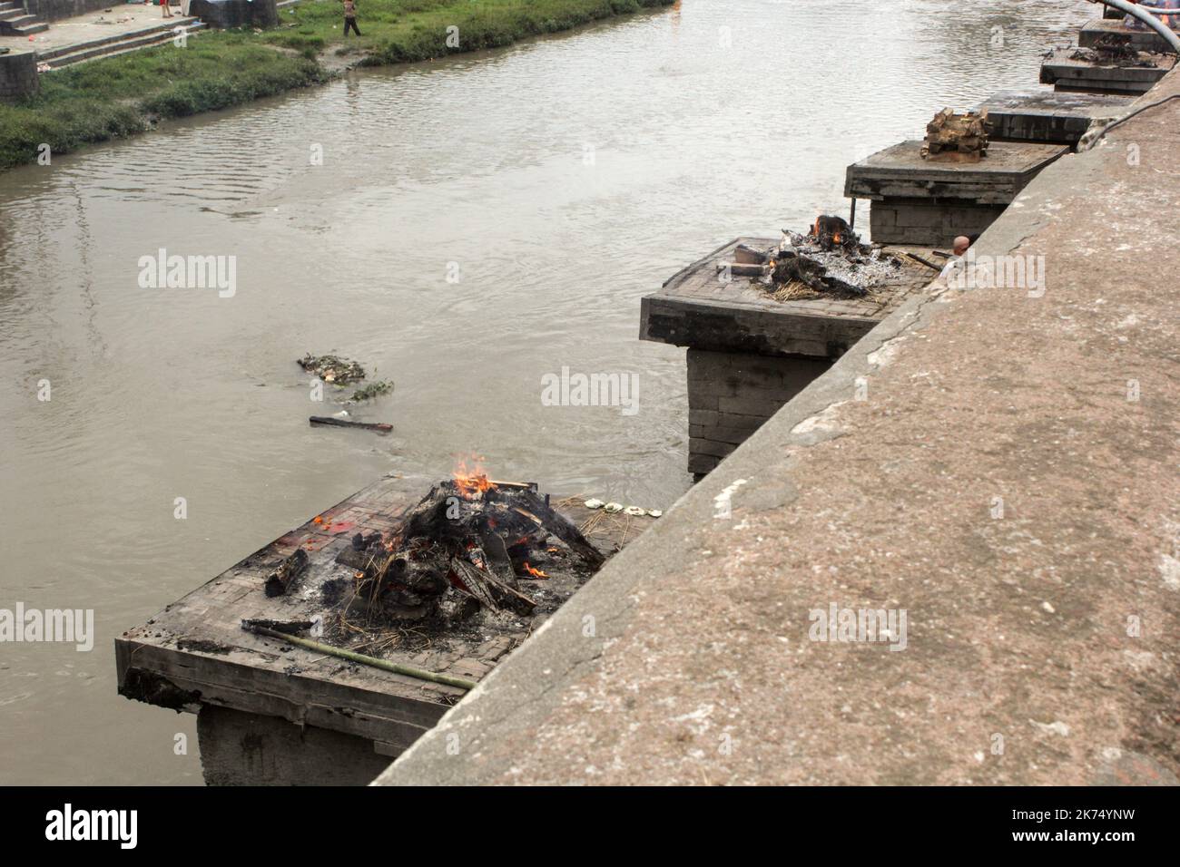 This temple is used primarily for outdoor cremation of the dead. The bodies are transported 24 hours after the death to the temple and then burned for 3 hours before seeing ashes thrown into the Bagmati River that runs through the temple. Only members of the royal family are cremated directly in front of the temple of Pashupatinath. Stock Photo