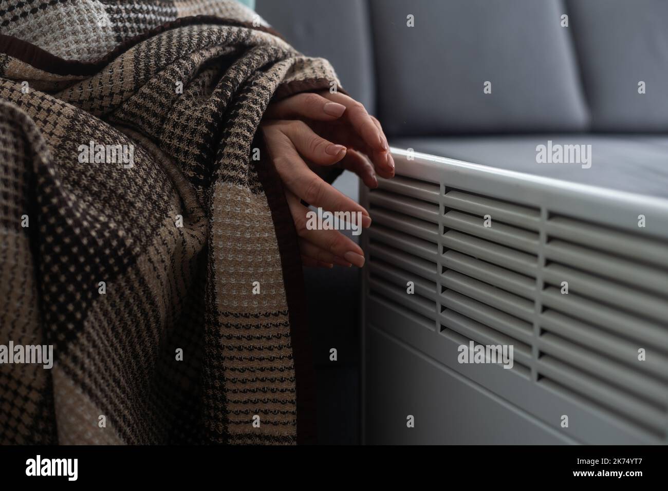 Girl warms up the frozen hands above hot radiator, close up. Woman