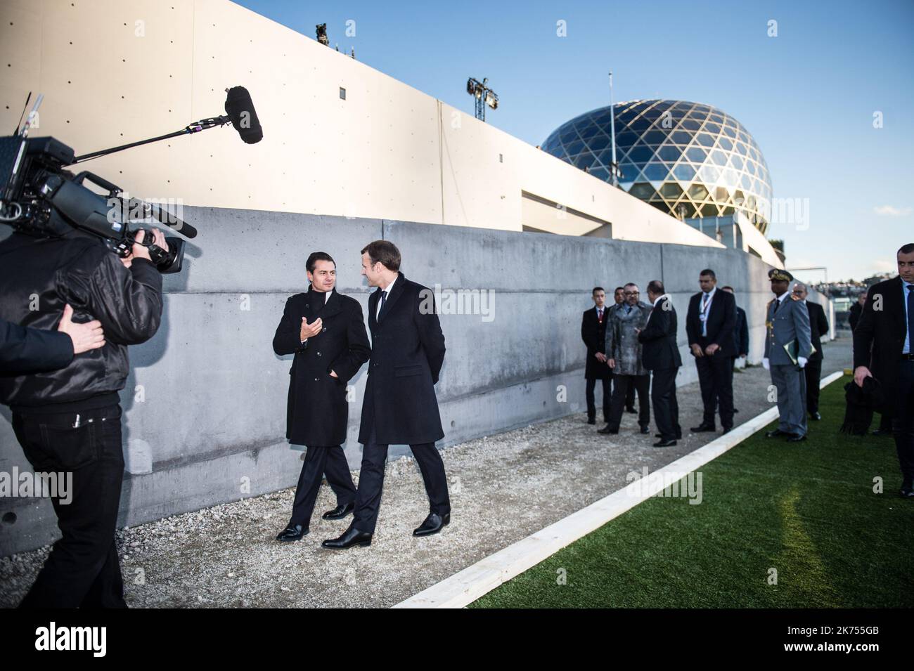 French President Emmanuel Macron (L) and Mexican President Enrique Pena Nieto talk upon their arrival to the One Planet Summit on December 12, 2017, at La Seine Musicale venue on the ile Seguin in Boulogne-Billancourt, southwest of Paris.  Stock Photo