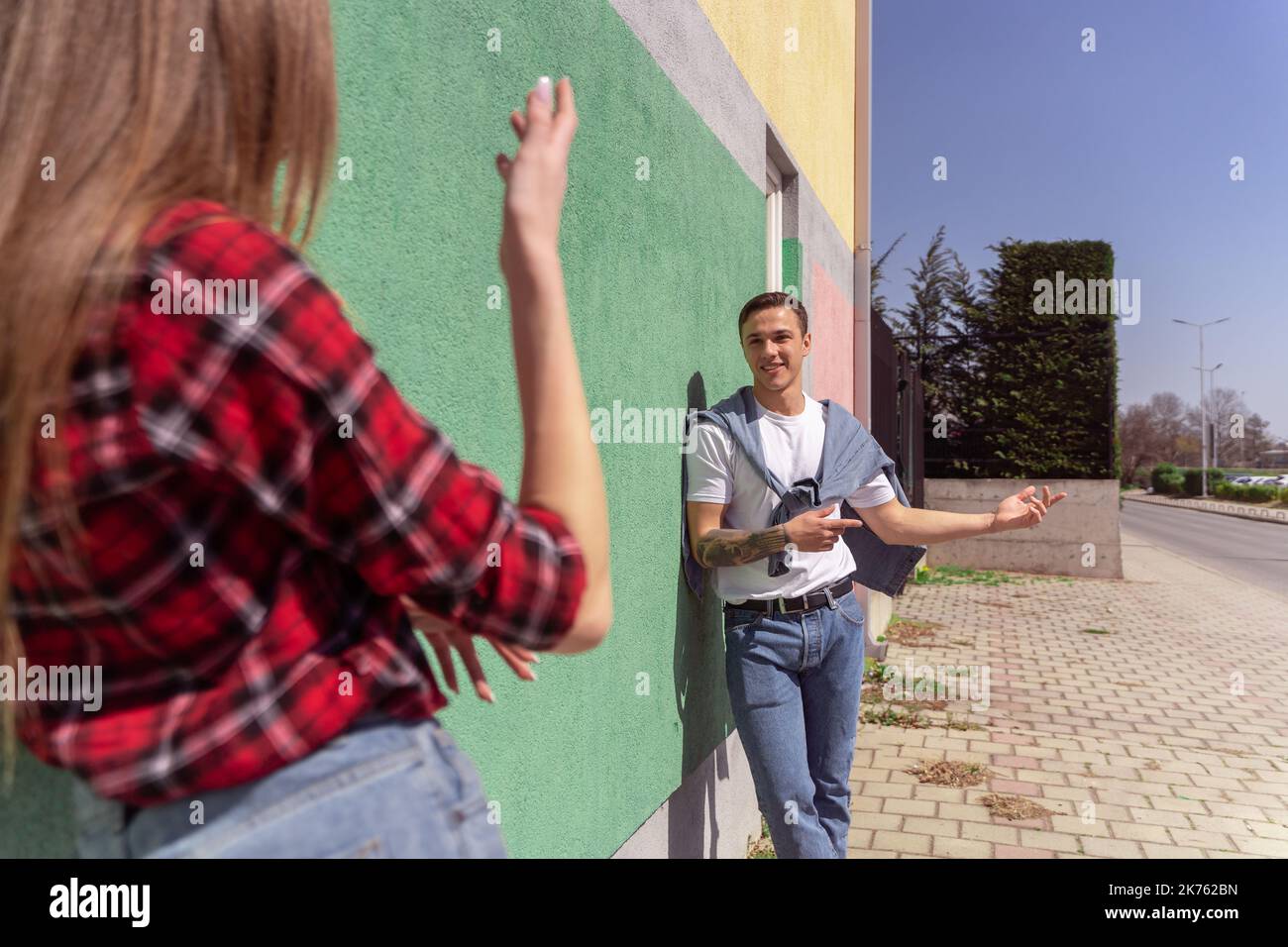 Cute couple talking outside while leaning on the gren wall Stock Photo