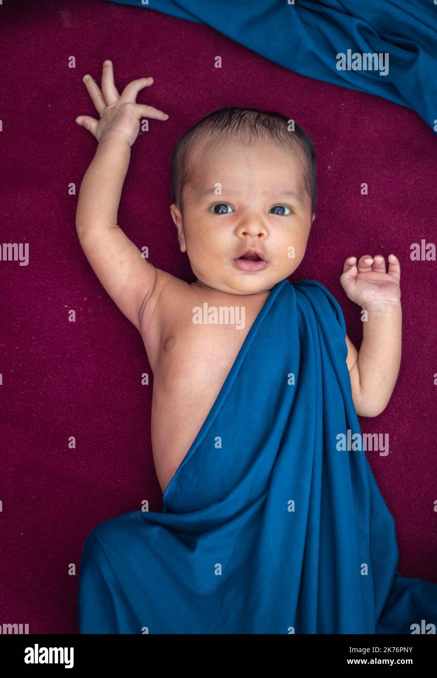 newly born baby laying on red velvet cloth with cute facial expression from different angle Stock Photo