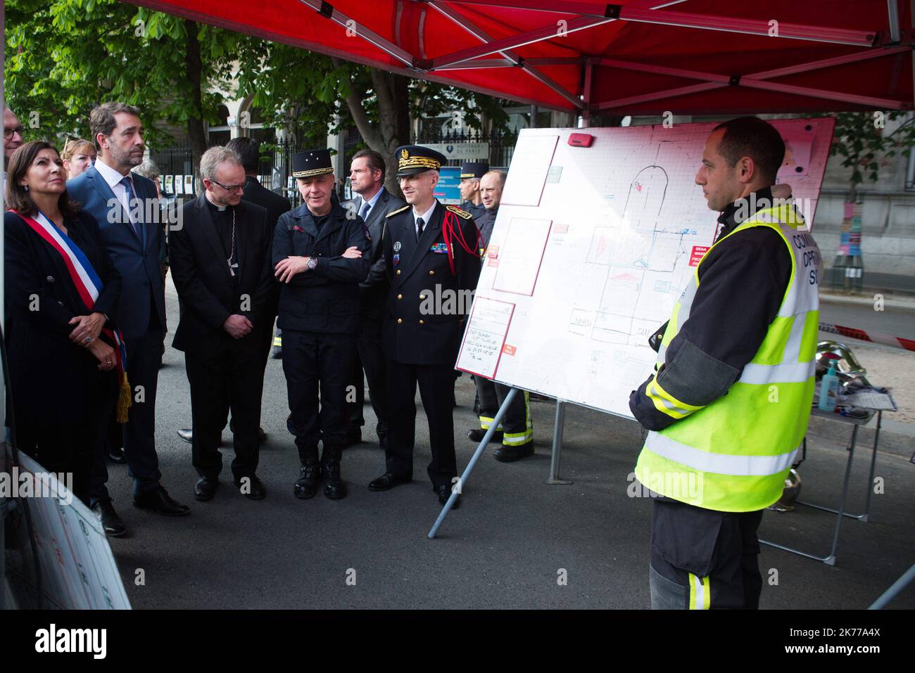 Jean-Claude Gallet General of the fire fighters of paris, Jean-Marc Chauve, French Interior Minister Christophe Castaner, Paris prefect Didier Lallement, Paris mayor Anne Hidalgo, and other officials walk by Notre Dame cathedral on April 18, 2019 in Paris. France paid a daylong tribute on April 18, 2019 to the Paris firefighters who saved Notre Dame Cathedral from collapse, while construction workers rushed to secure an area above one of the church's famed rose-shaped windows and other vulnerable sections of the fire-damaged landmark.  Stock Photo