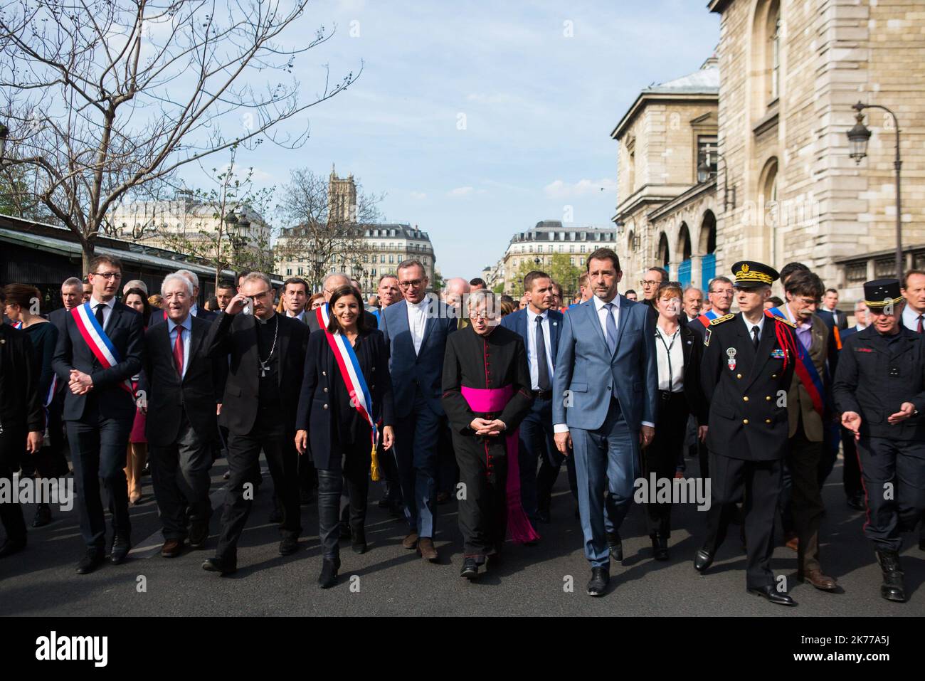 French Interior Minister Christophe Castaner (C), Notre Dame cathedral rector Jean-Marc Chauvet (2L), Paris mayor Anne Hidalgo (L), Paris prefect Didier Lallement (3R) and other officials walk to Notre Dame cathedral on April 18, 2019 in Paris. France paid a daylong tribute on April 18, 2019 to the Paris firefighters who saved Notre Dame Cathedral from collapse, while construction workers rushed to secure an area above one of the church's famed rose-shaped windows and other vulnerable sections of the fire-damaged landmark  Stock Photo