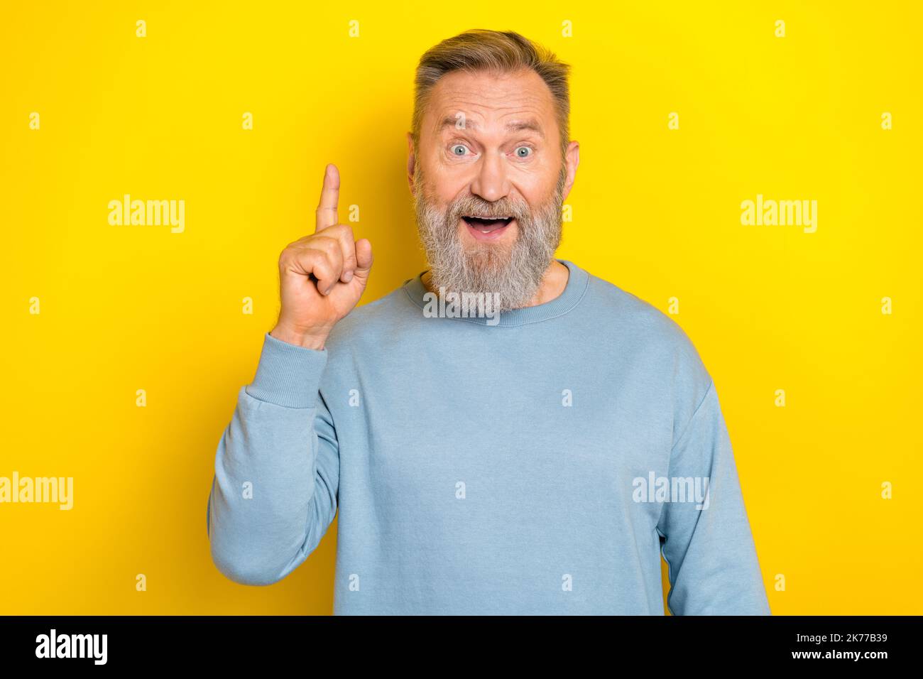 Photo of shocked impressed retired guy wear blue sweater pointing finger up isolated yellow color background Stock Photo