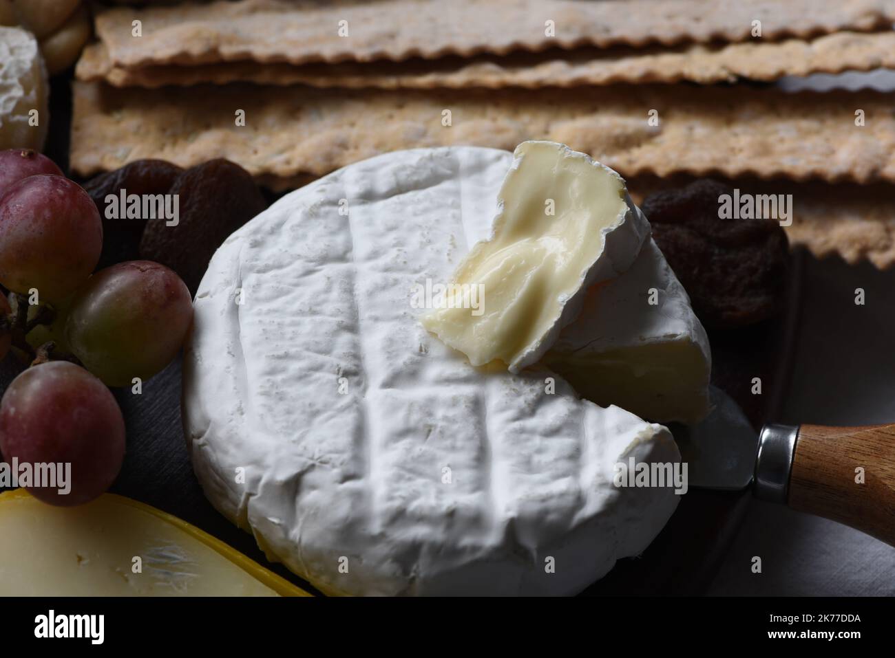 A wheel of brie cheese with purple grapes and crackers Stock Photo Alamy