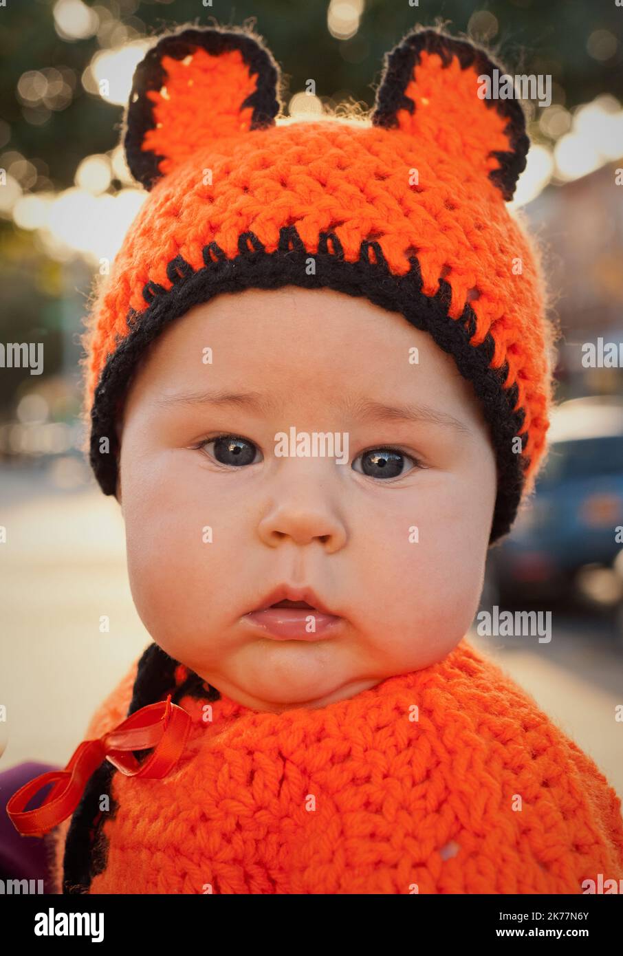 A baby is wearing a unique costume grandma made out of colorful yarn