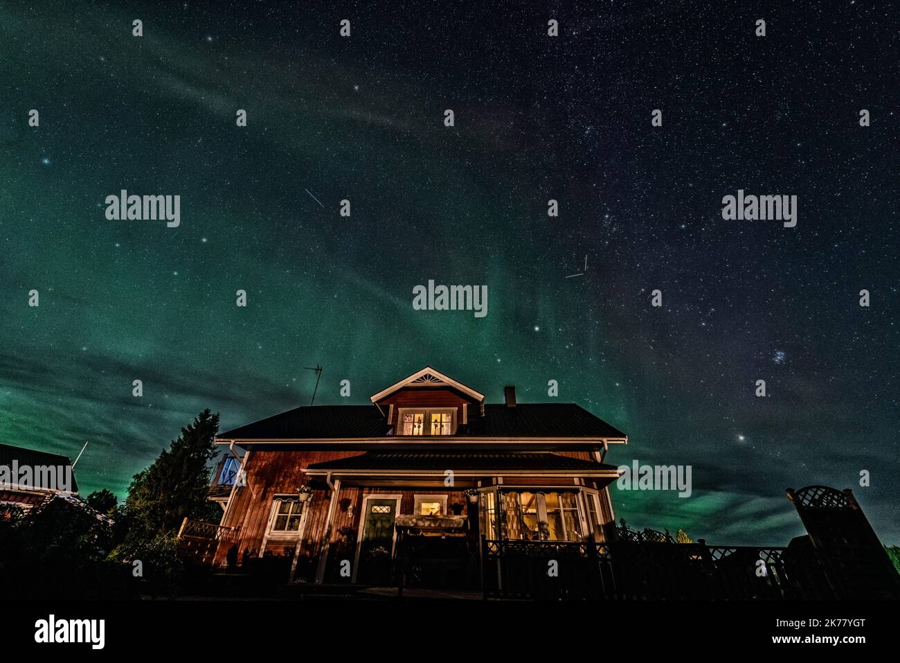 Star Trails and Aurora - Long exposure to capture star trails and light aurora borealis over Swedish countryside house, night scenery Stock Photo