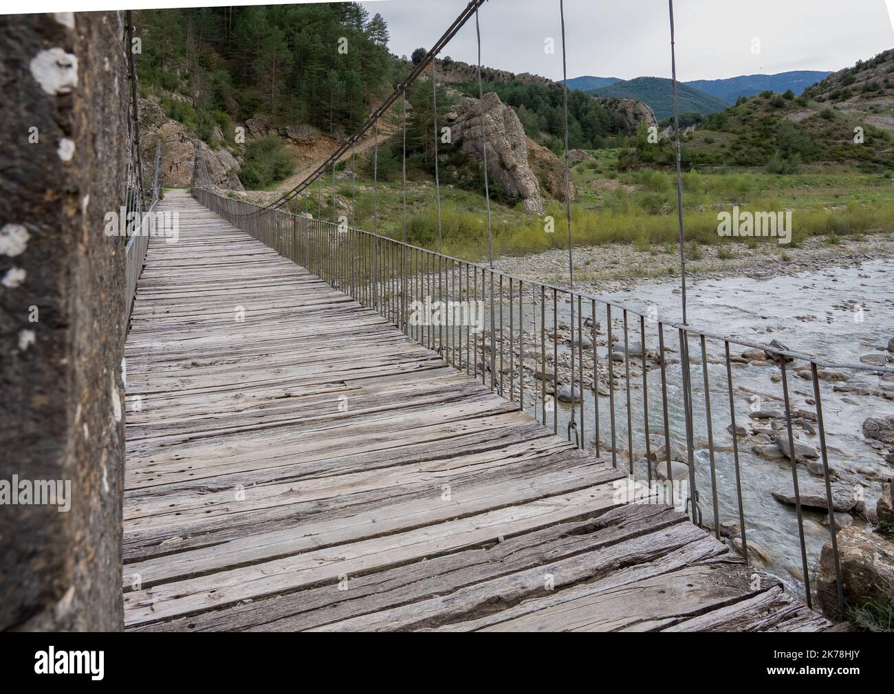 a stone pier, cable stay suspension foot bridge over a mountain river Stock Photo