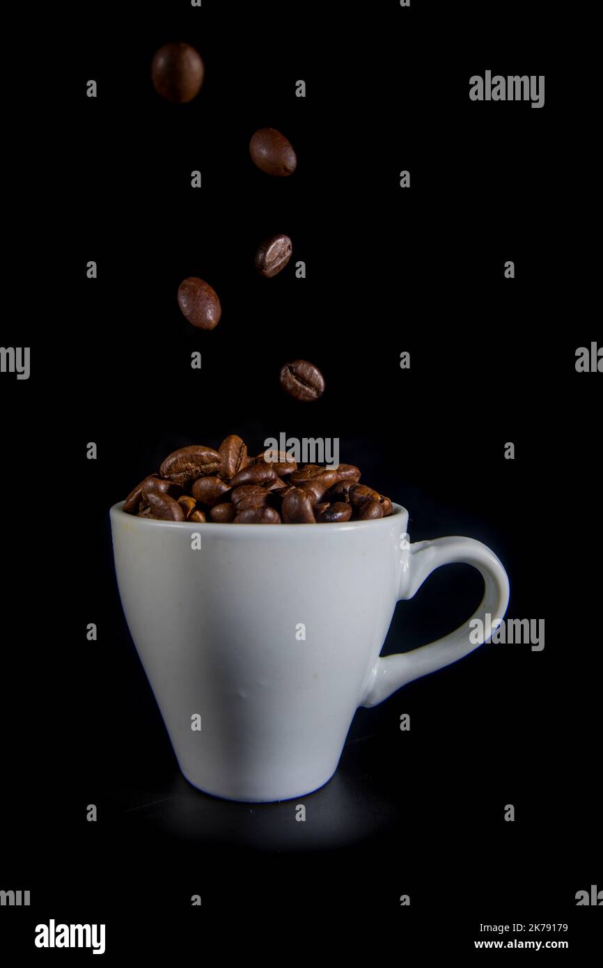 White cup with coffee beans on a black background Stock Photo - Alamy