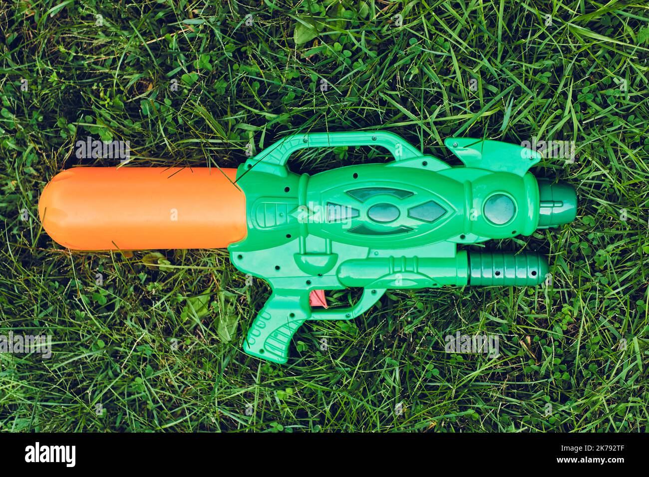 Plastic toy water pistols are lying in the grass in the backyard Stock
