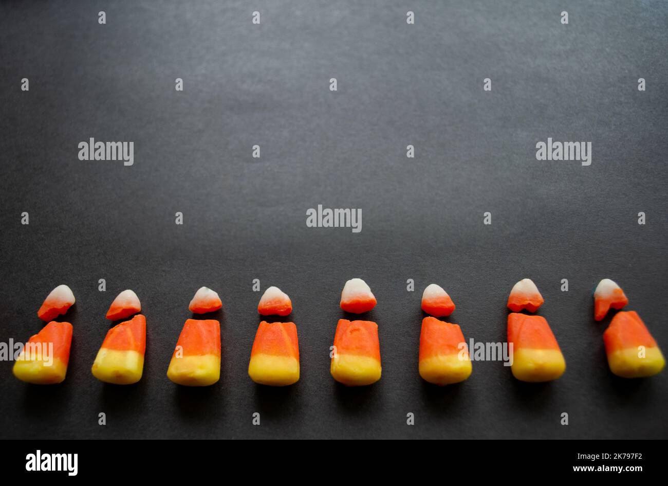 Broken candy corn look like small bad teeth. Black background. Copy