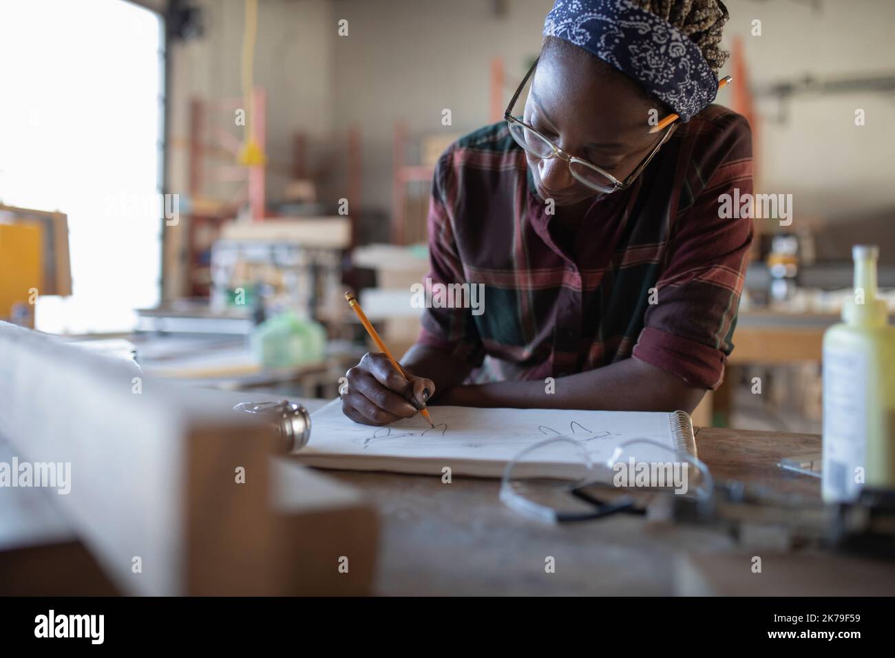 Mid adult woman drawing on work bench in community workshop Stock Photo