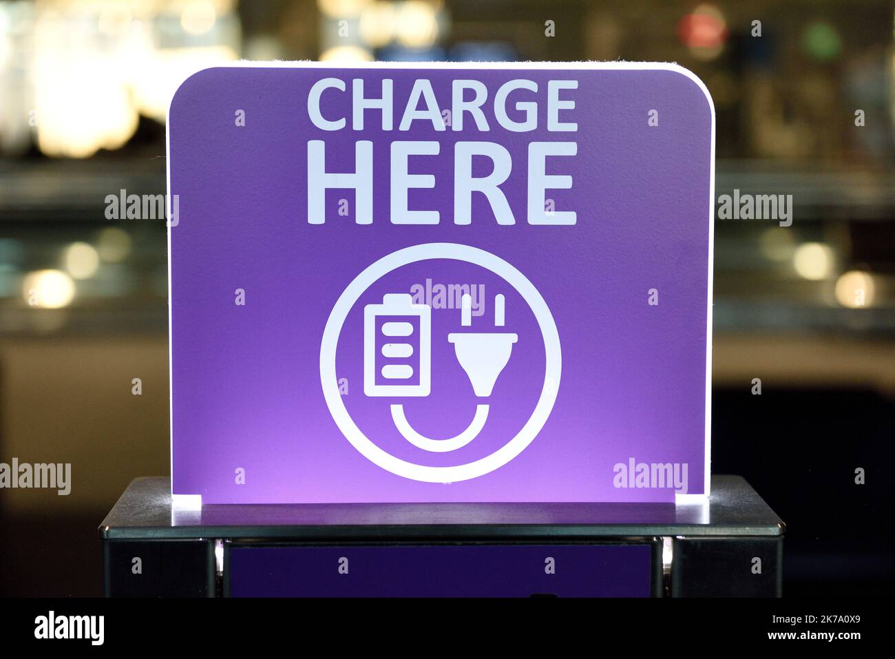 Public electrical charging station, Charge Here sign, device recharging area, power outlets Stock Photo