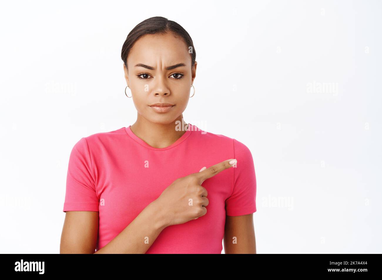 Disappointed woman frowns, points finger right, shows advertisement