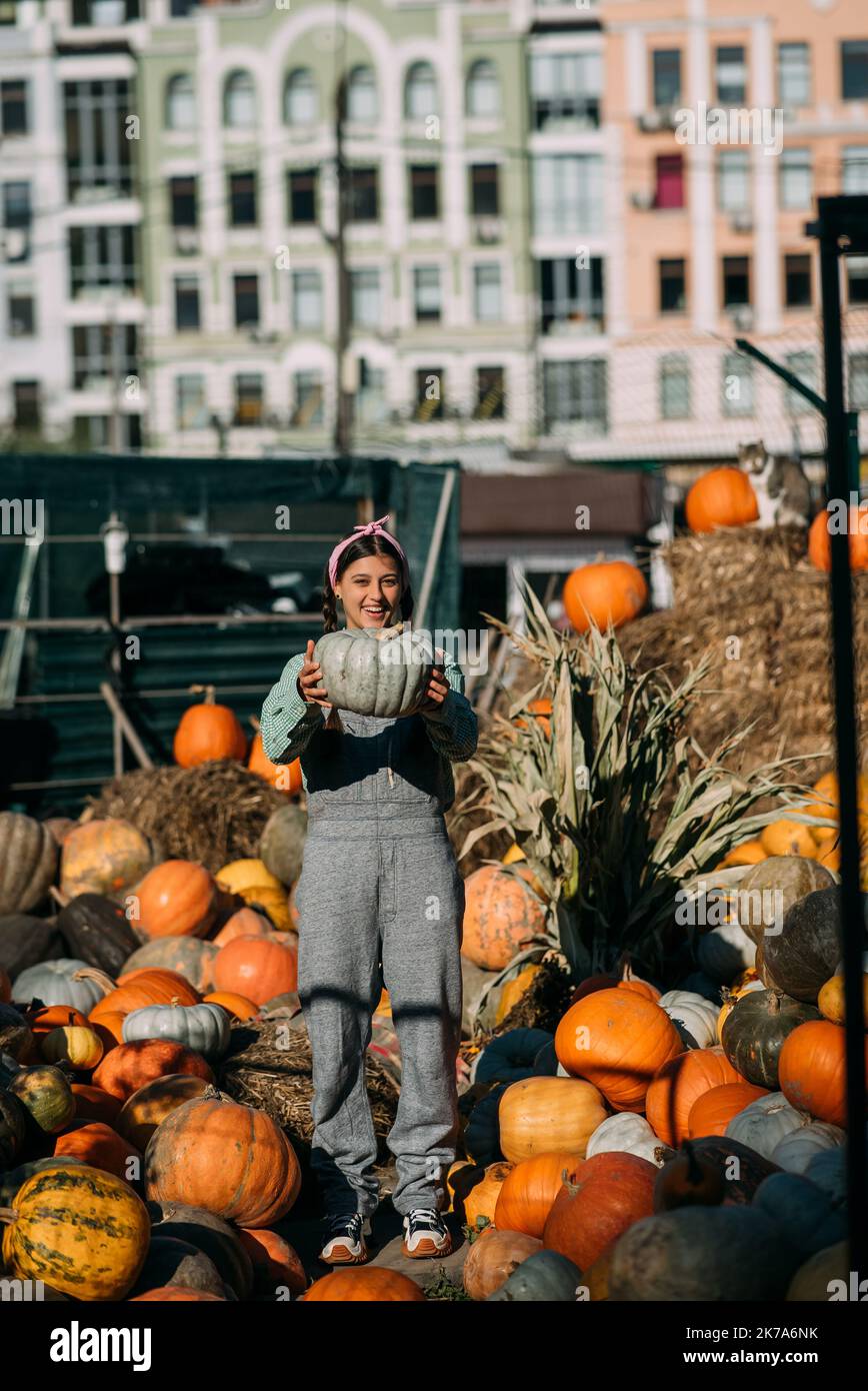 Happy farmer woman in a denim jumpsuit holds ripe pumpkin Stock Photo