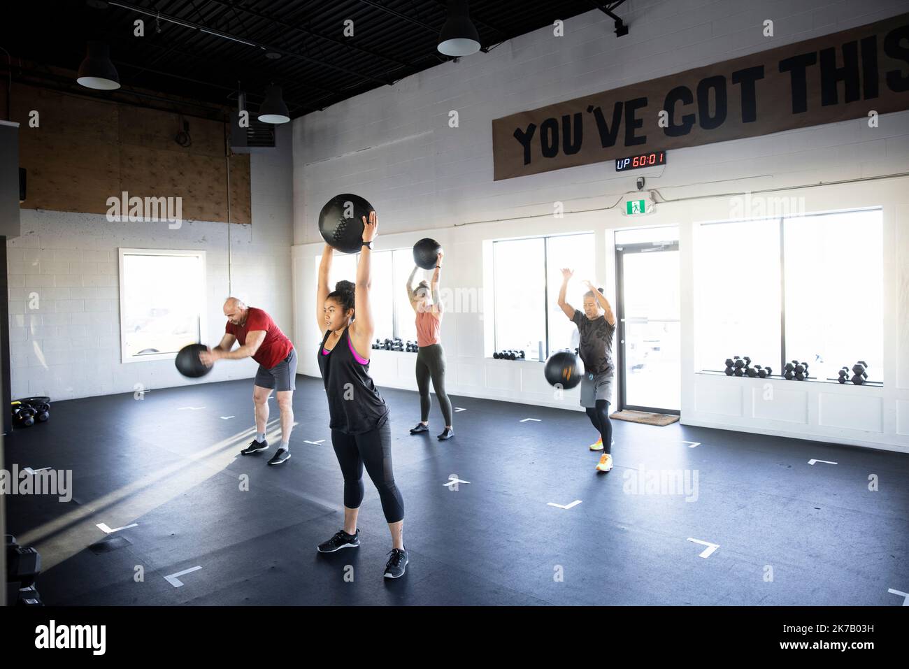 Group fitness class doing medicine ball lifts in gym studio Stock Photo