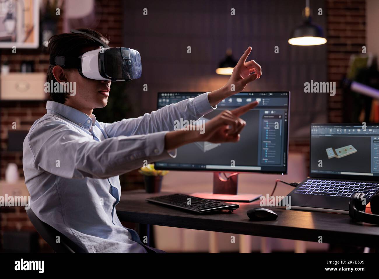 Male freelancer using vr glasses on industry production, engineering technical product with virtual reality headset and computer. Developing machinery engine component with cad software app. Stock Photo
