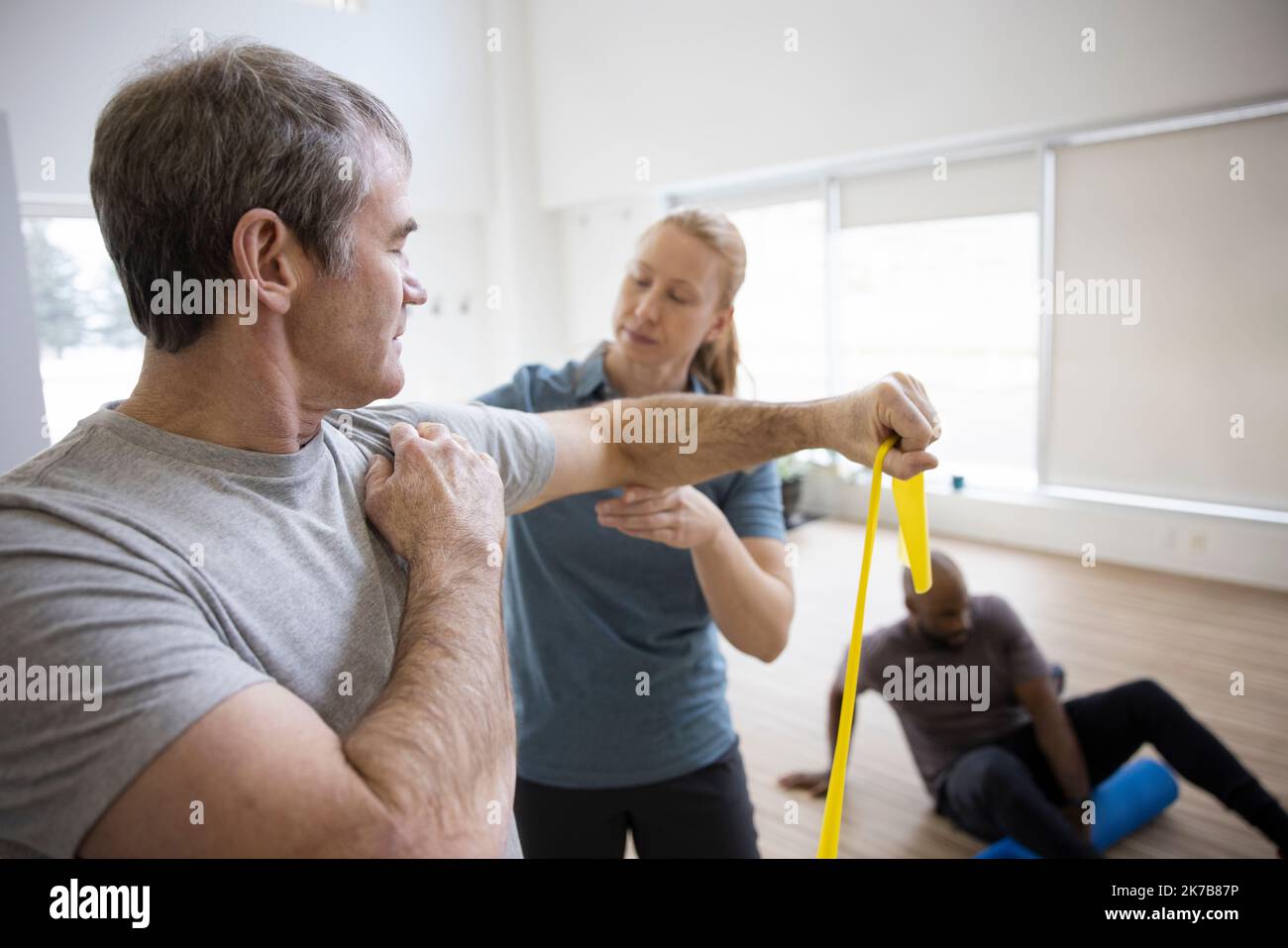 Physiotherapist guiding patient with resistance band exercise in clinic