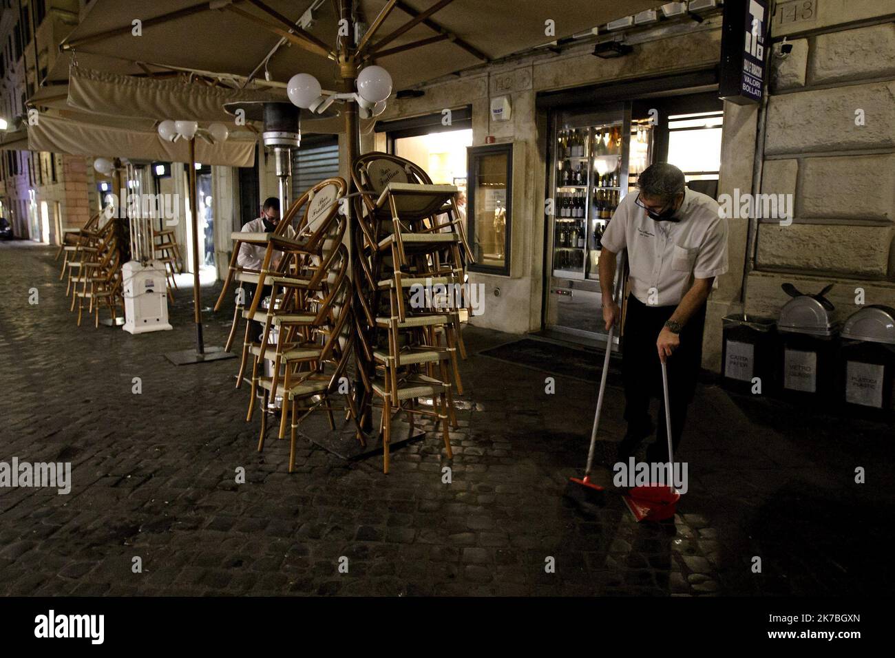 A waiter, wearing a protective face mask, cleans a terrace outside a coffee bar in Via Frattina, before a curfew imposed by the region of Lazio from midnight to 5 a.m to curb the COVID-19 infection, caused by the novel coronavirus. Rome, Italy, 24 October 2020 Stock Photo