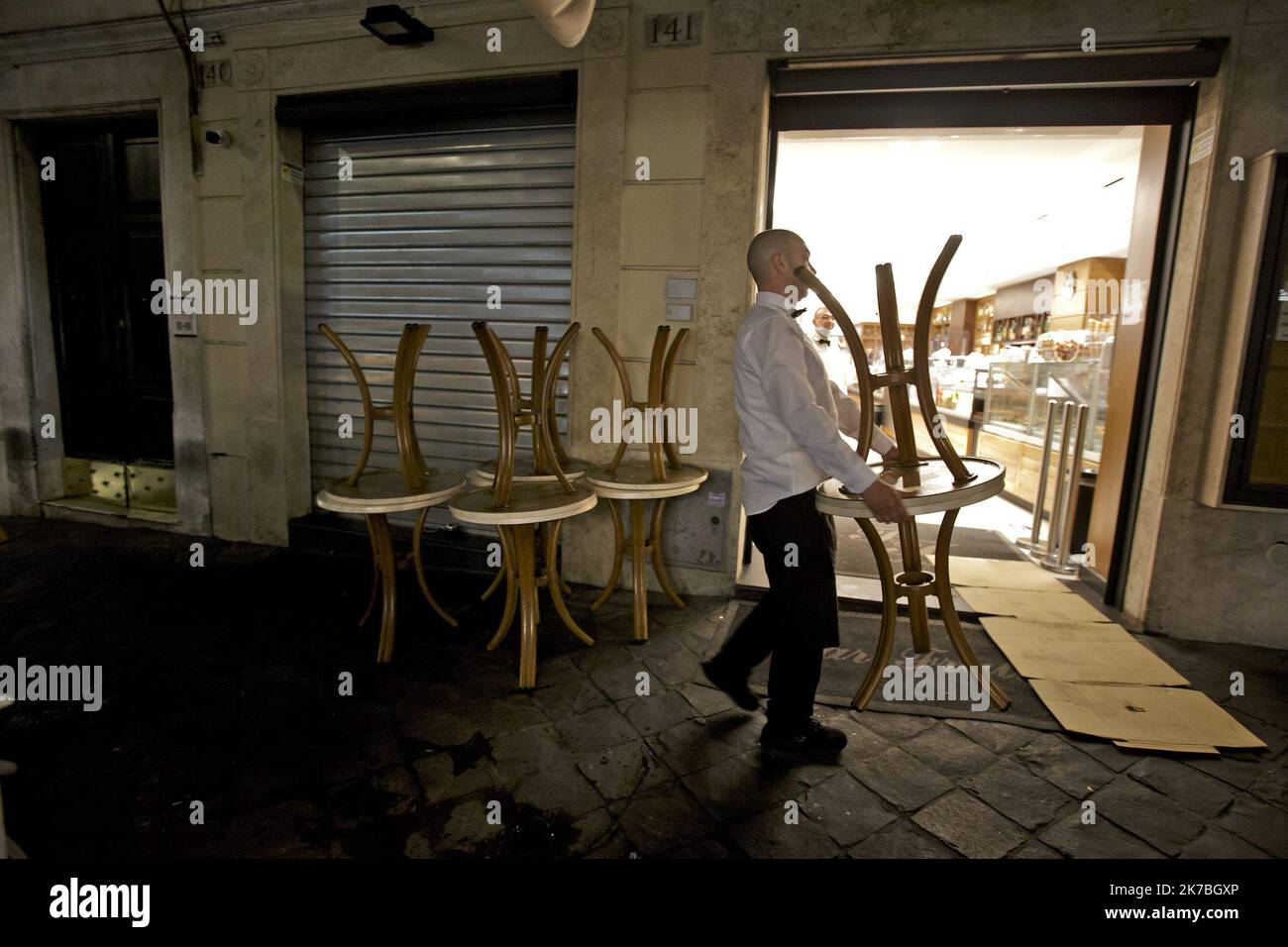 A waiter, wearing a protective face mask, carries chairs outside a coffee bar in via Frattina, before a curfew imposed by the region of Lazio from midnight to 5 a.m to curb the COVID-19 infection, caused by the novel coronavirus. Rome, Italy, 24 October 2020 Stock Photo
