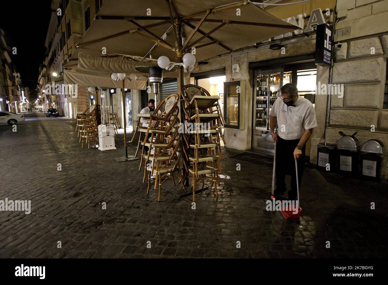 A waiter, wearing a protective face mask, cleans a terrace outside a coffee bar in Via Frattina, before a curfew imposed by the region of Lazio from midnight to 5 a.m to curb the COVID-19 infection, caused by the novel coronavirus. Rome, Italy, 24 October 2020 Stock Photo