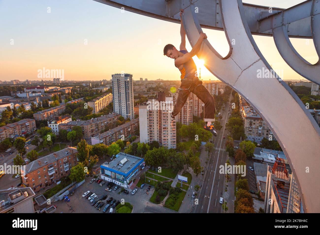 Urban climbing free solo rock climber hanging on element of roof of