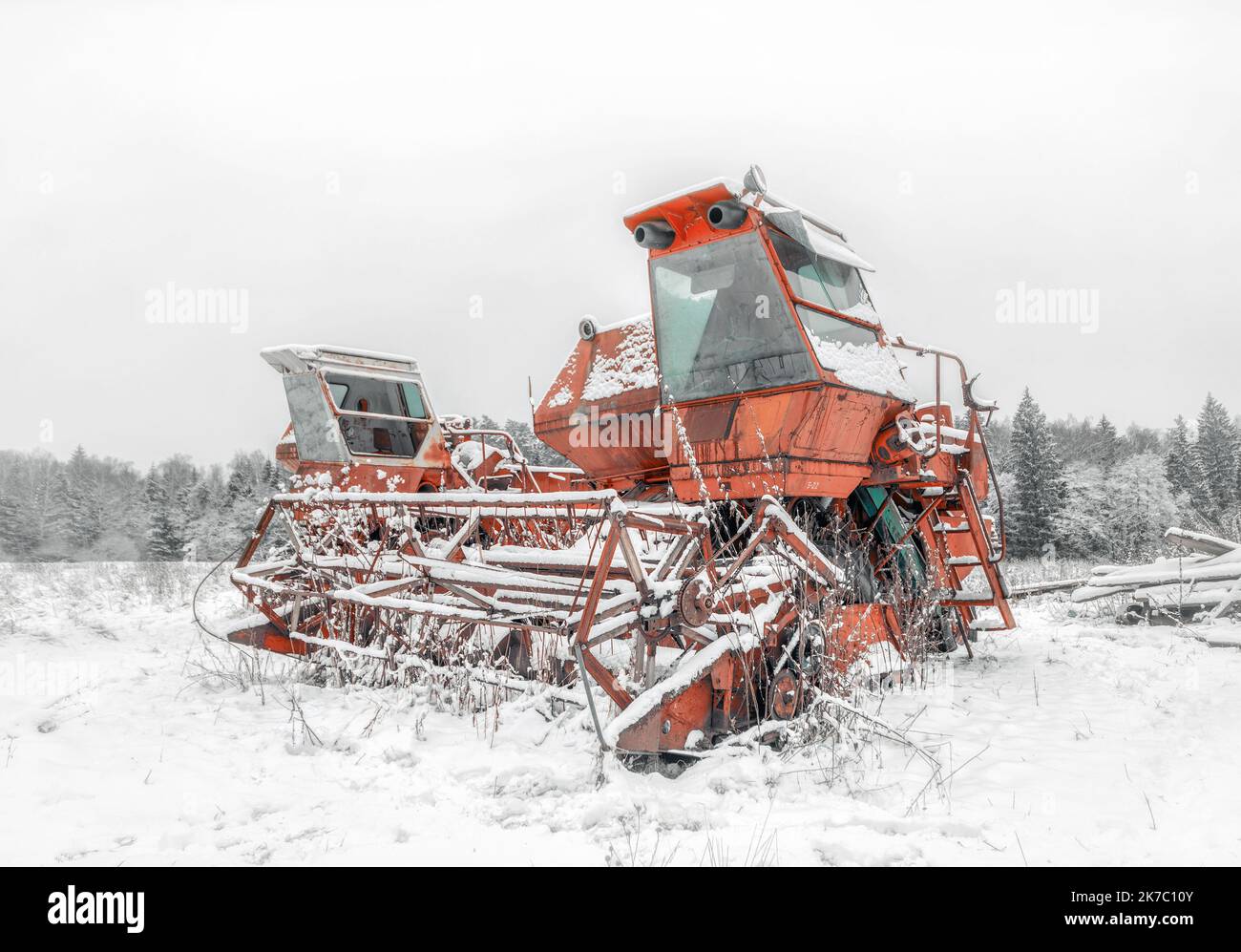 Red broken frozen combine harvester on a snowcovered field. Old broken