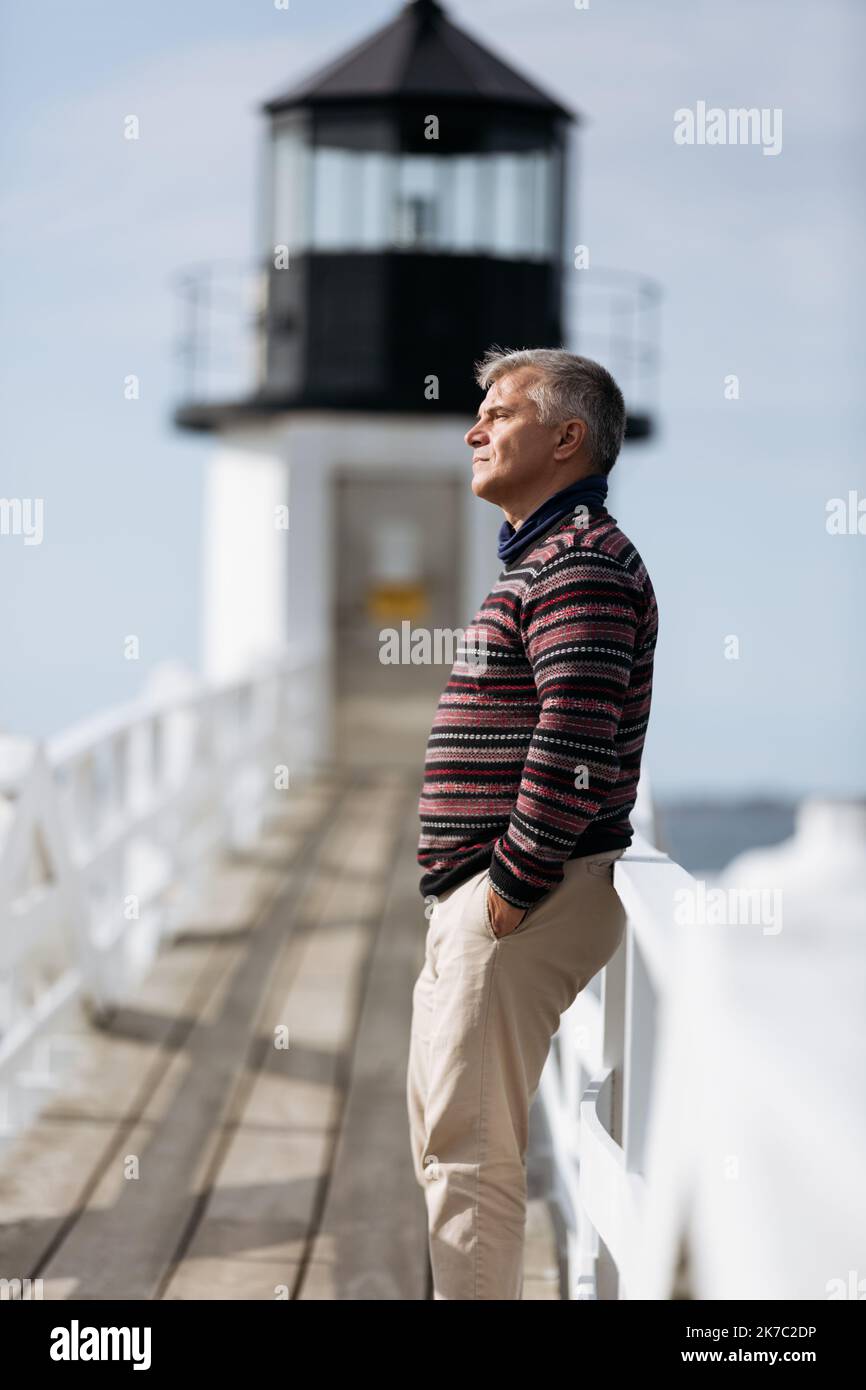 Senior man leaning on the fence looking ahead thoughtfully Stock Photo