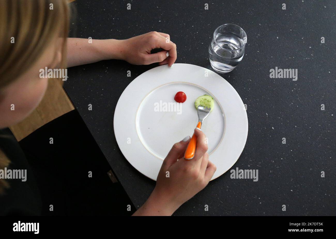 ©PHOTOPQR/L'ALSACE/Vanessa MEYER ; ; 02/06/2021 ; Une jeune fille anorexique devant une assiette presque vide avec une tomate cerise et une rondelle de concombre et un verre d'eau. Les troubles du comportement alimentaire ont augmenté pendant la crise sanitaire. - anorexia Stock Photo